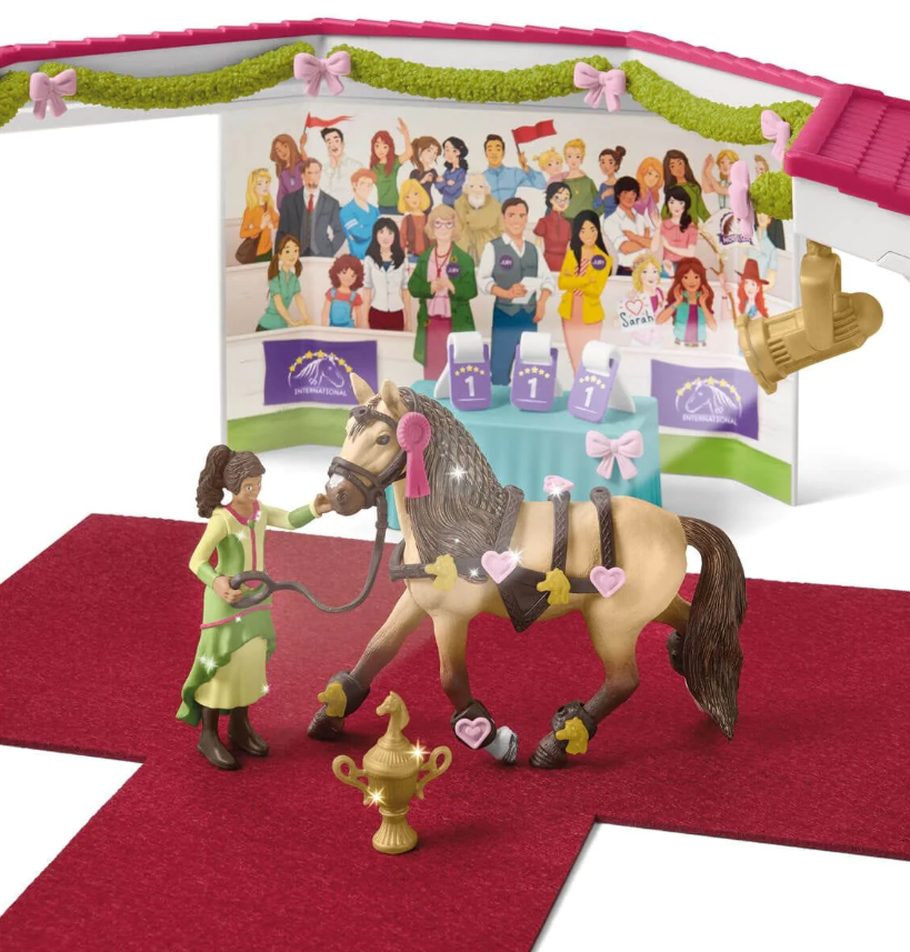 Toy Schleich horse and rider with a display of people and trophies in the background in Ireland