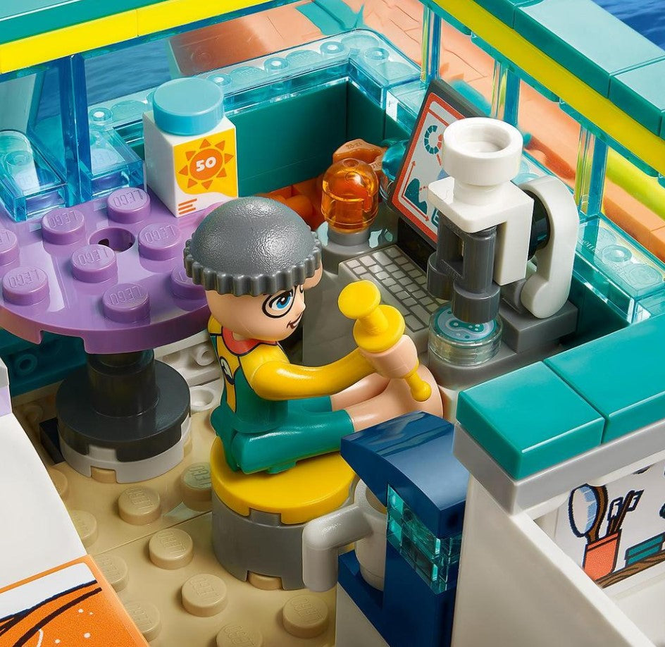 Close-up of a LEGO set with a character sitting at a desk, surrounded by colorful elements.