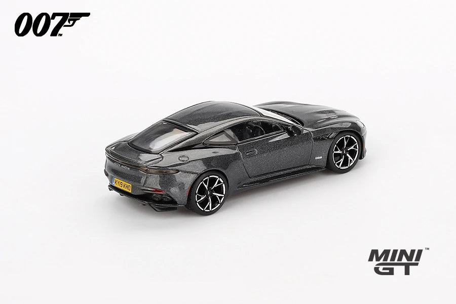 James Bond Aston Martin DBS grey RHD prototype viewed from the rear left showing the rear light strip, boot spoiler, black roof and yellow number plate