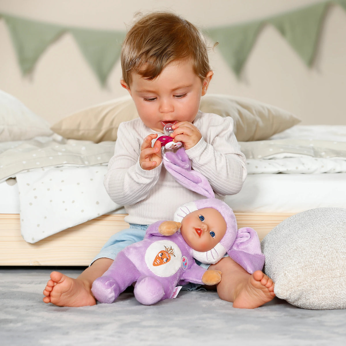 BABY born Funny Bunny on child's lap while child holds the attached dummy