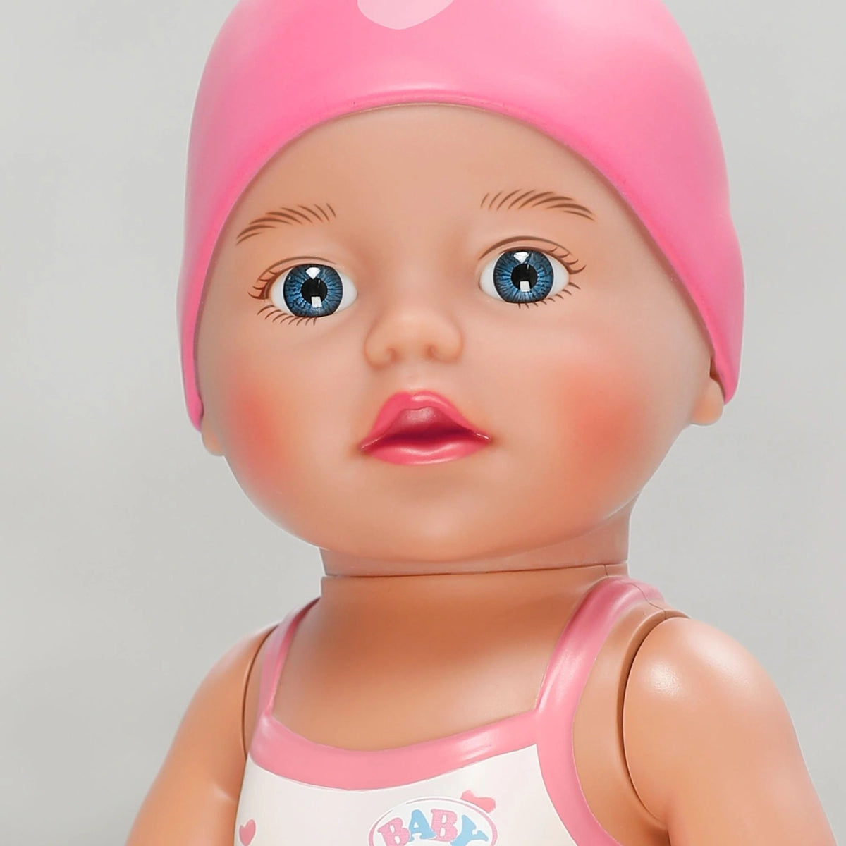 Close up of Baby Born Swimming Lizzie 30cm face with blue eyes and pink swim cap