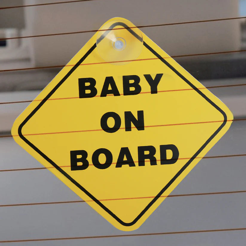 Babylo baby on board sign attached to a car rear window using a suction cup, yellow diamond sign with black border and baby on board text visible through glass