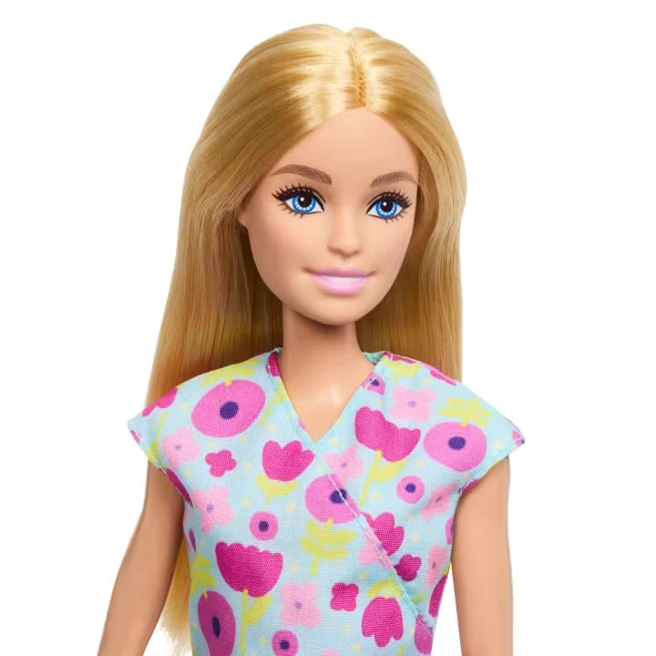 Close-up of the blonde Barbie Baby Doctor doll with blue eyes, pink lips and long straight hair, wearing a light turquoise medical scrub top decorated with pink and purple flowers.