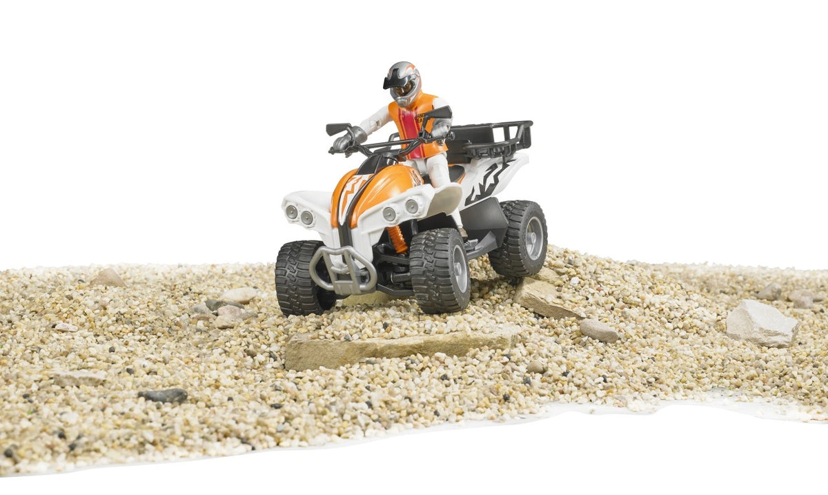 Bruder bworld Quad with Driver 63000 travelling over a rocky gravel surface with a helmeted rider, orange and white bodywork and black tread tyres