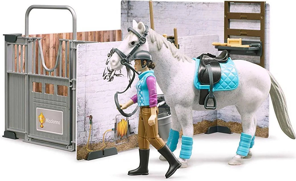 Figure leading a white horse beside the Bruder Bworld horse barn scene with stable tools