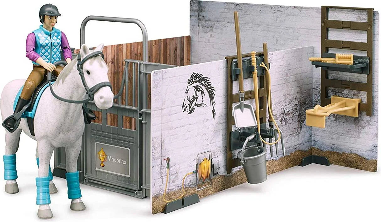 Rider figure sitting on a white horse next to the Bruder Bworld stable panels and grooming tools