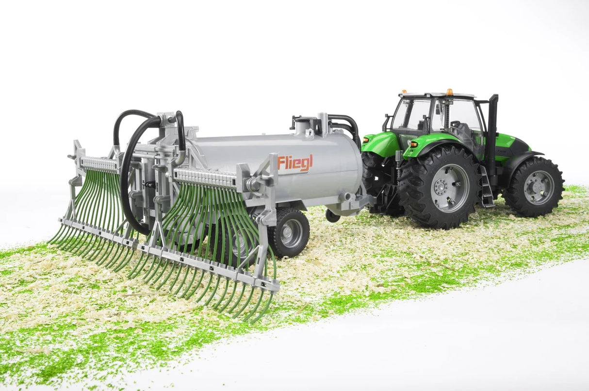 Silver Fliegl farm toy barrel trailer with green spread tubes attached to a green tractor