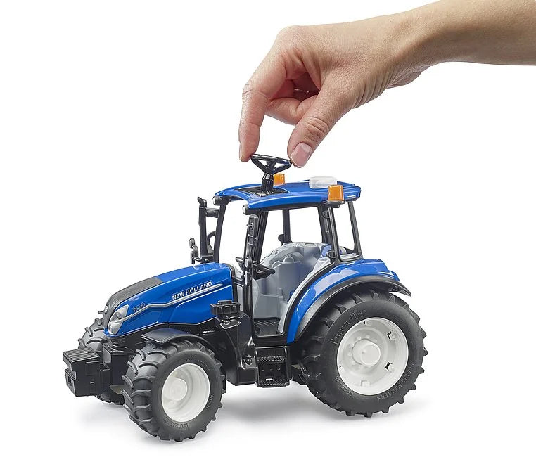 Hand using roof steering rod to control Bruder New Holland T5.120 farm tractor toy model in Ireland