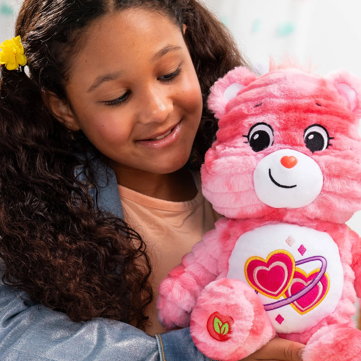 Child hugging Care Bears Color Splash Love-A-Lot Bear 35 cm (14 inch) plush highlighting cuddly design in Ireland.