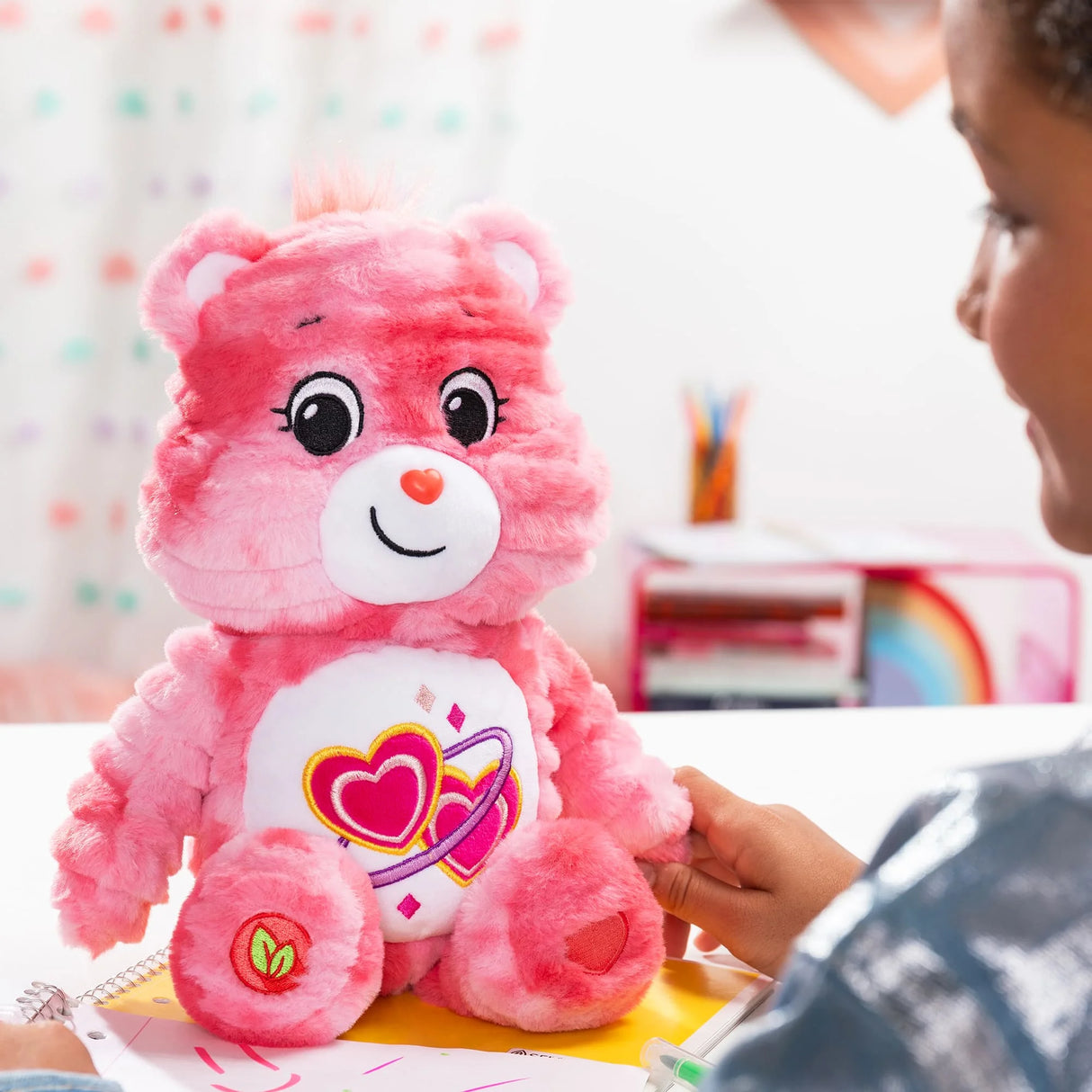 Care Bears Color Splash Love-A-Lot Bear plush on a desk showing pink tie-dye fur and cheerful face in Ireland.