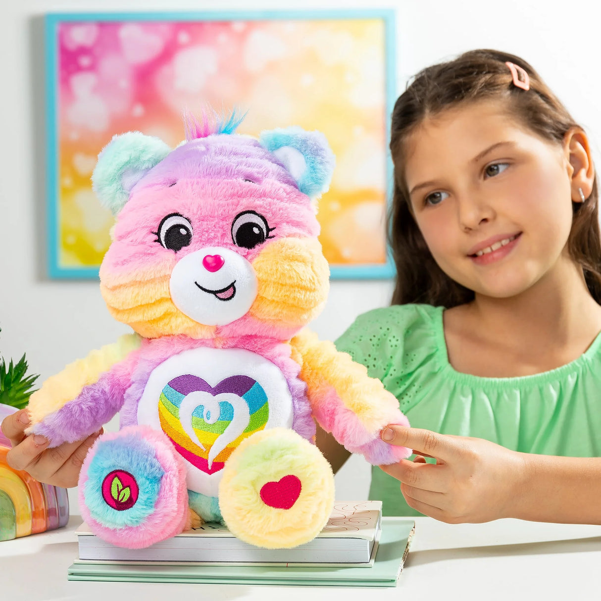 Child smiling with Care Bears Color Splash Togetherness Bear showing multicolour fur and rainbow heart badge in Ireland.