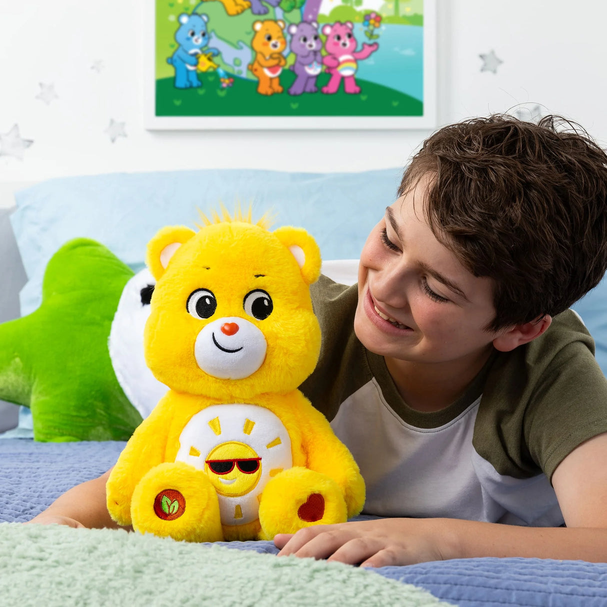 Child lying on bed hugging Care Bears Medium Plush Funshine Bear showing bright yellow fur and cheerful face in Ireland.
