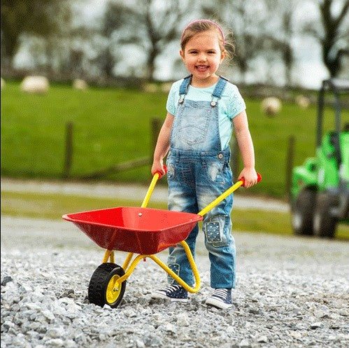 Smiling child playing with Rolly Metal Wheelbarrow outdoors, Ireland