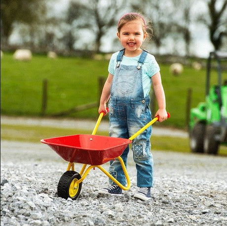 Smiling child playing with Rolly Metal Wheelbarrow outdoors, Ireland