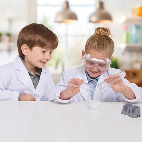 Two kids in lab coats using the Cool Chemistry kit to mix liquids and learn about reactions