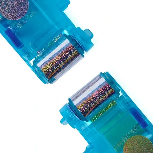 Close-up of two translucent turquoise Cool Maker foil cartridges containing multicoloured glittery shimmer foil rolls against a white background.