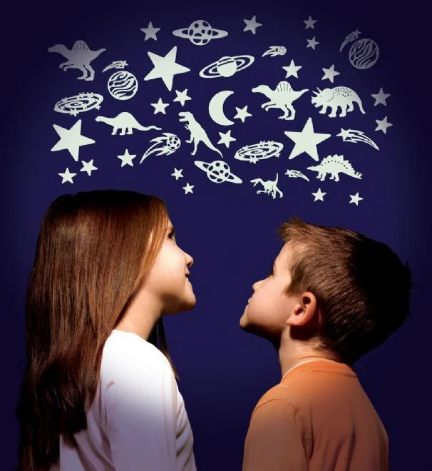 Two children looking up at glow-in-the-dark dinosaur and star stickers arranged across a dark wall.