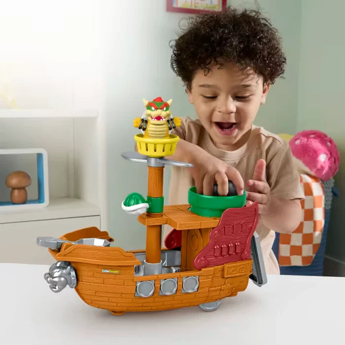Child playing with Fisher-Price Little People My Mario Bowser’s Airship playset with Bowser figure, green shell and black cannonball