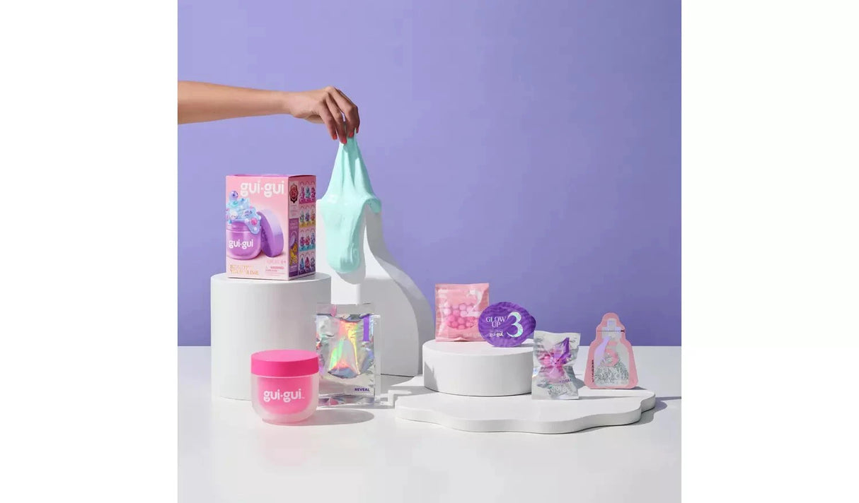 Gui Gui Single Pack box and pink jar displayed on white pedestals with teal slime being stretched, alongside booster, glow up and sparkle sachets