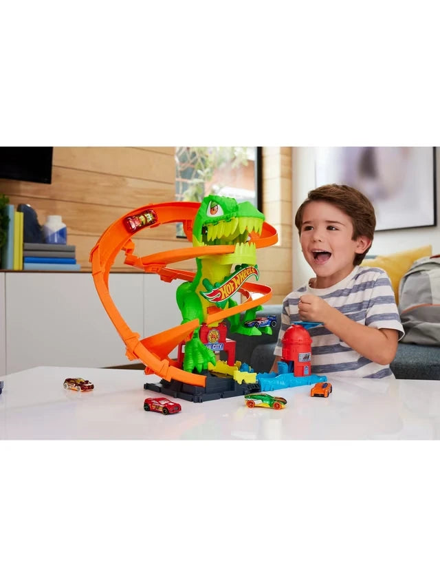 Hot Wheels City T-Rex Fire Station being played with by a child, showing the T-Rex, spiral track and Hot Wheels cars