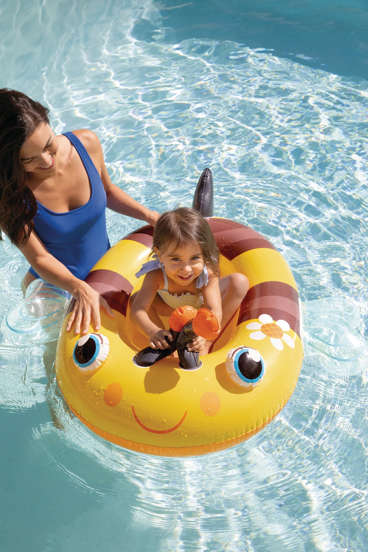 Yellow Bee Intex Pool Cruisers boat float with a child seated inside and an adult beside it in a pool