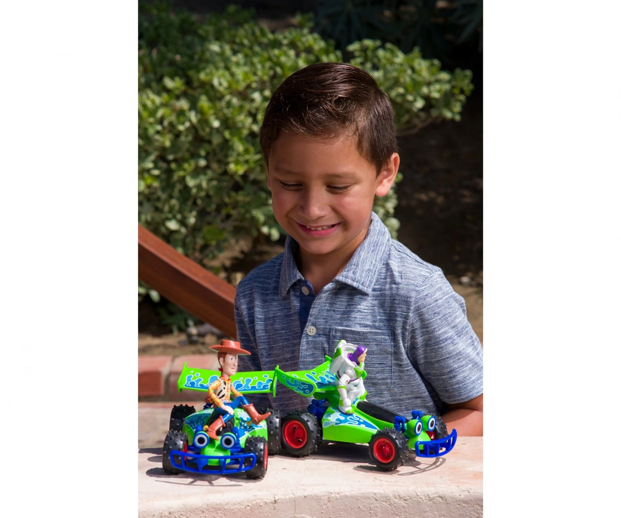Child shown outdoors with two Toy Story RC buggies and a green remote control