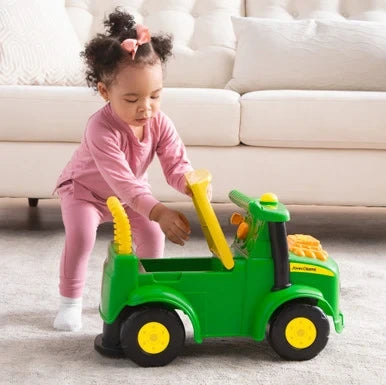 John Deere Johnny Tractor with child lifting yellow seat to open storage compartment