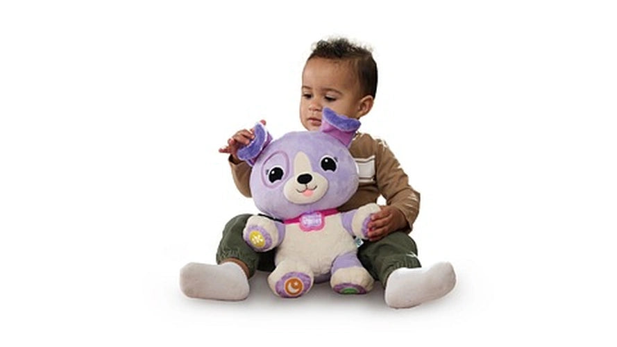 Young child sitting with LeapFrog My Best Pal Violet between their legs and touching the purple puppy's ear