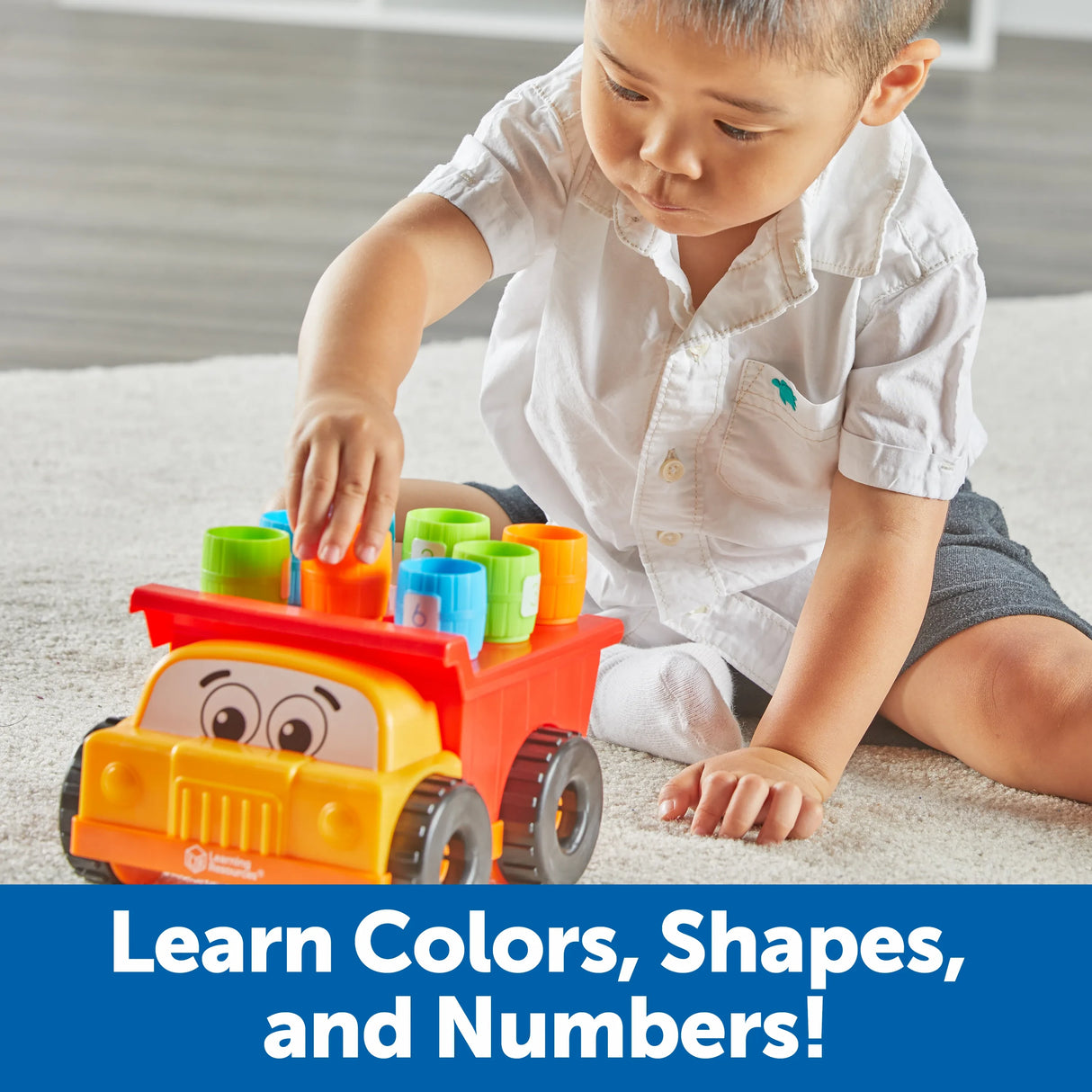 Child playing with Learning Resources Tony the Peg Stacker Dump Truck and coloured barrels