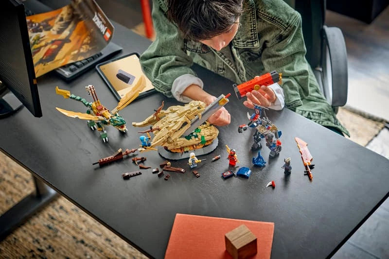 LEGO NINJAGO dragon, mech and minifigure pieces spread across a table during building