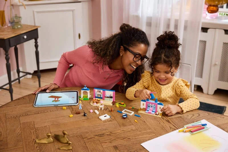 Adult and child building LEGO Cinderella Animal Friends Castle on a table with a tablet nearby
