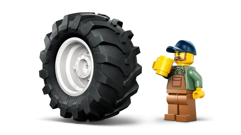 Large black LEGO tractor tyre with metallic wheel hub displayed next to LEGO City farmer minifigure wearing blue cap, green shirt and brown overalls holding a yellow mug