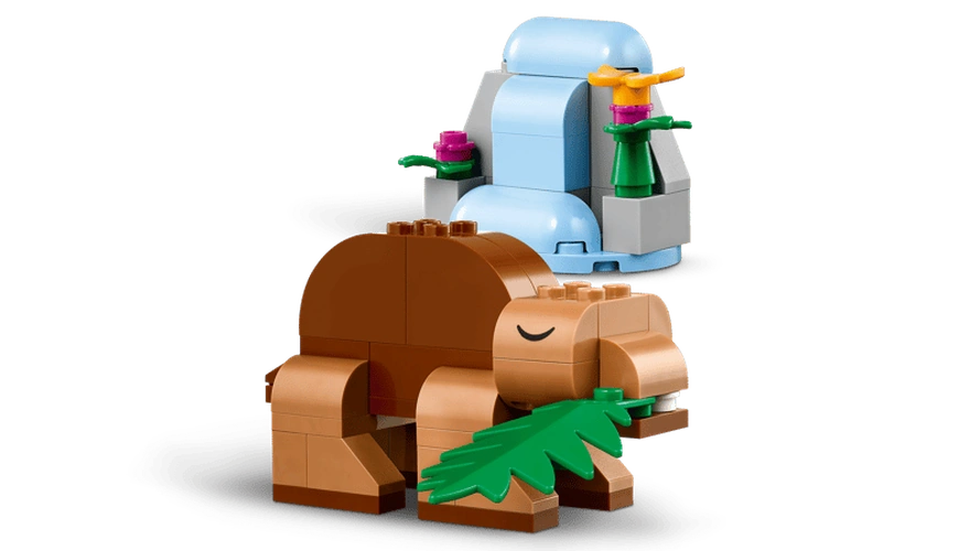 Brown LEGO Classic Creative Dinosaurs model holding a green leaf beside a blue waterfall with colourful flowers