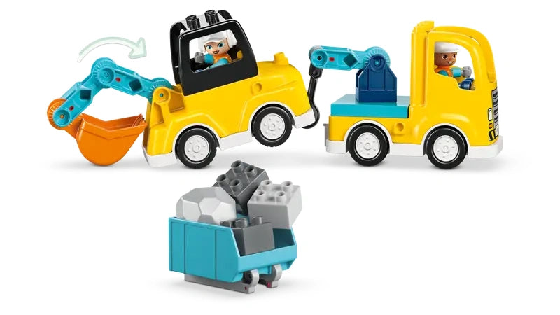 Two connected LEGO DUPLO yellow construction vehicles with teal excavator arm, wheeled cart, grey bricks and rounded stone piece