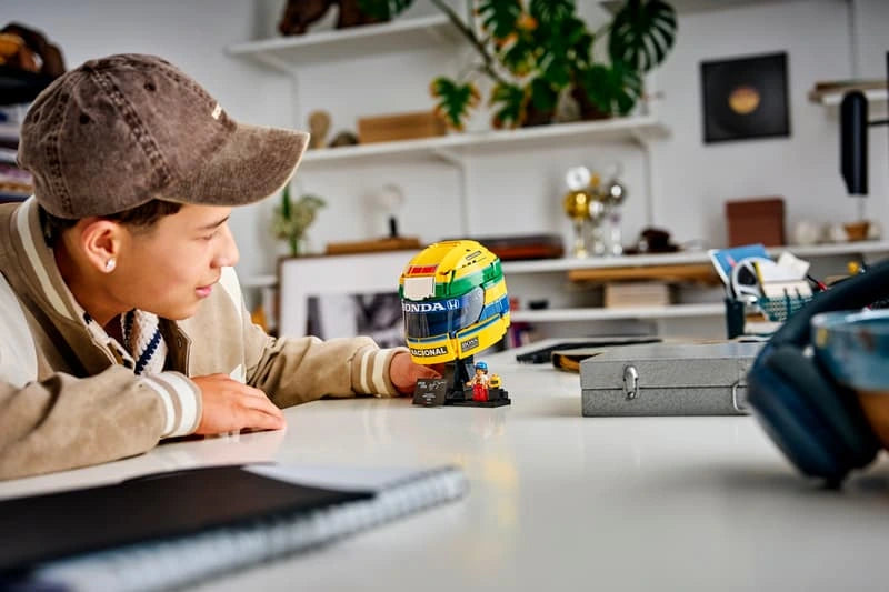 Person looking at completed LEGO Ayrton Senna Helmet 43024 displayed on a desk beside a metal case