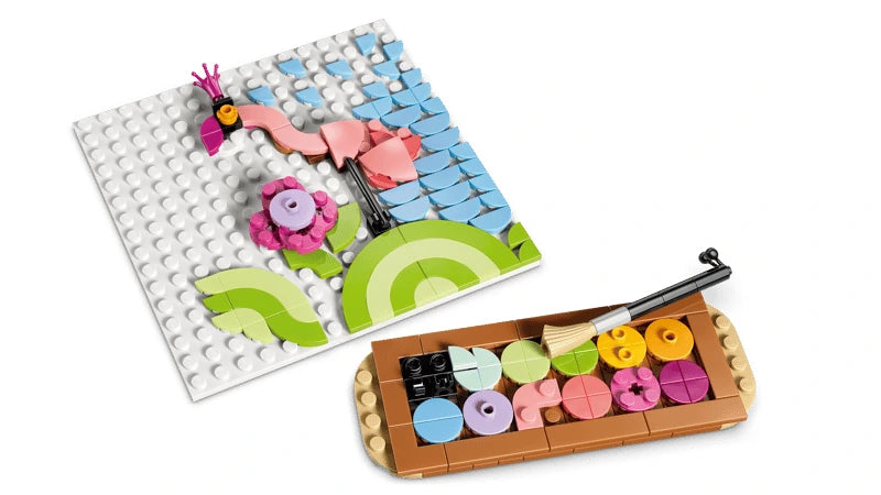 LEGO flamingo sketch build beside an open paint palette and brush