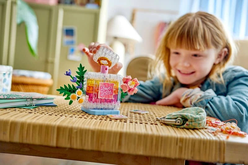 Child looking at LEGO floral perfume bottle build on a table with loose pieces nearby
