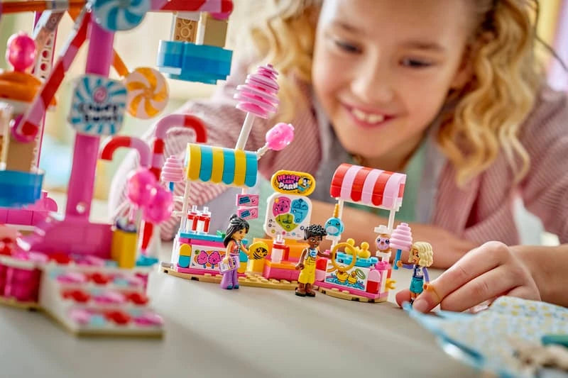 Child playing with LEGO Friends Candy & Cupcake Ferris Wheel set with minidolls and fairground stand