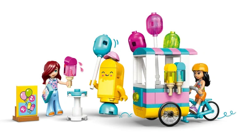 Assembled LEGO Friends ice cream and balloon cart in white, pink and teal, attached to a light blue bicycle with Liann, Paisley and accessories