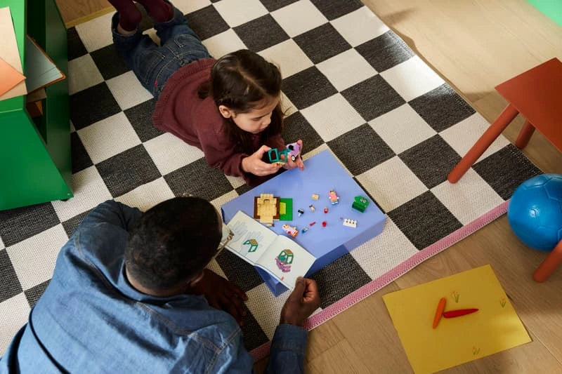 Child playing with LEGO Bluey pieces, purple car build and instruction booklet