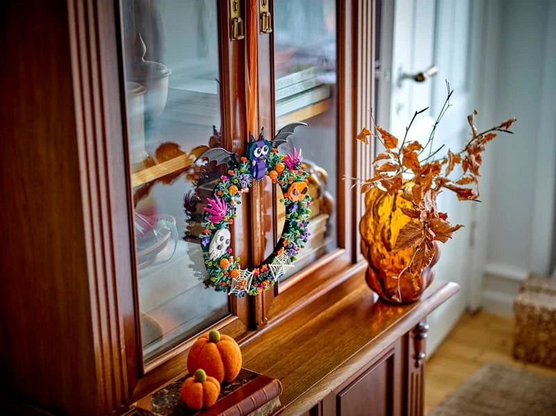 LEGO Halloween Wreath 40825 hanging from a wooden cabinet beside autumn decorations