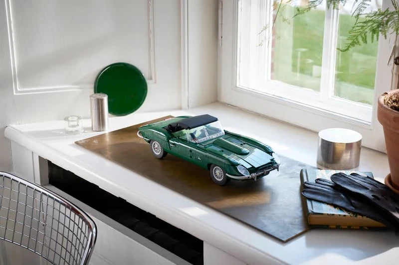 LEGO Icons Jaguar E-Type 11381 green car model displayed on a desk beside a window