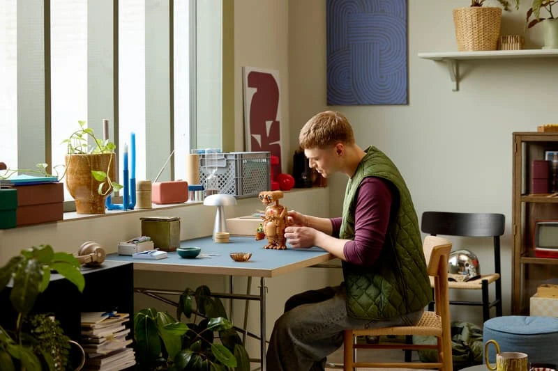 Adult builder positioning the LEGO Ideas E.T. the Extra-Terrestrial 21370 model on a desk