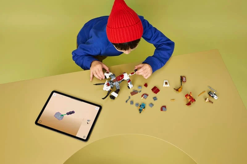 Child building a LEGO NINJAGO dragon beast set at a table with pieces and tablet instructions