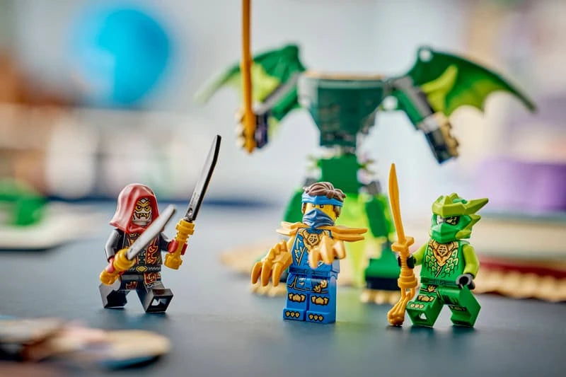 Three LEGO NINJAGO minifigures with a green dragon mech in the background