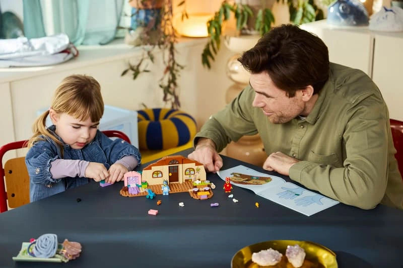 Child playing with LEGO Bluey school build, figures and instruction booklet at a table