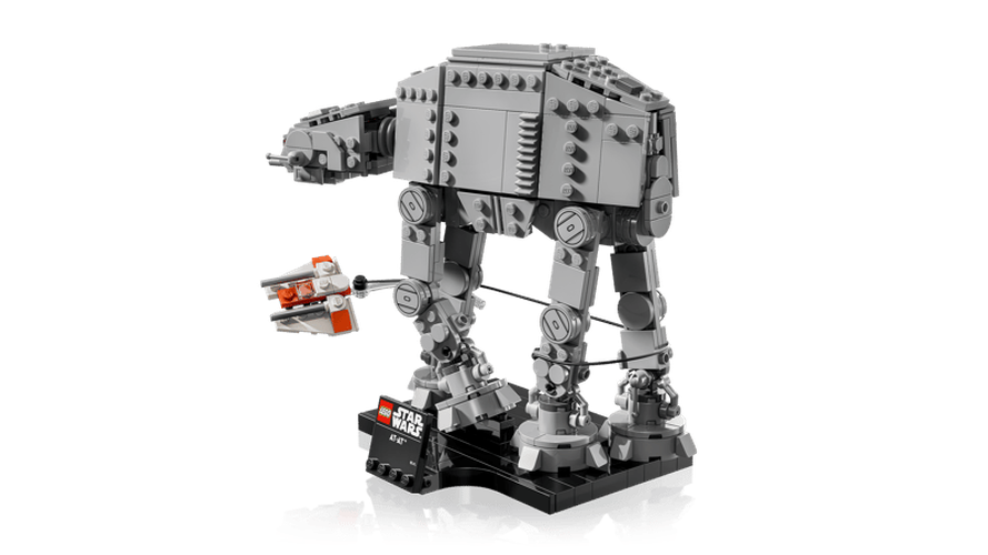 Side view of the completed LEGO Star Wars AT-AT walker on its black display stand, with the orange and white Rebel Snowspeeder and tow cable around the walker's legs.