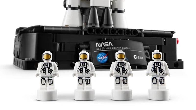 Four LEGO Technic NASA astronaut nanofigures lined up in front of the Artemis rocket display base