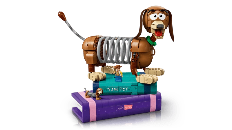 LEGO Slinky Dog model displayed on stacked purple and turquoise book builds with small character figures