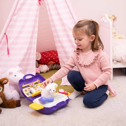 Child kneeling beside the open Little Pet Parlour Carry Case while grooming the white plush puppy with the brush, hair dryer and accessories nearby